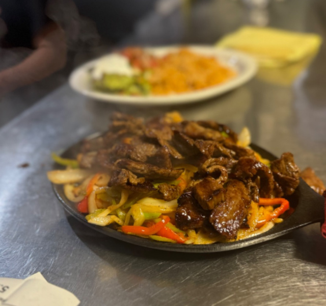 Sizzling steak fajitas with onions and bell peppers on a cast-iron skillet