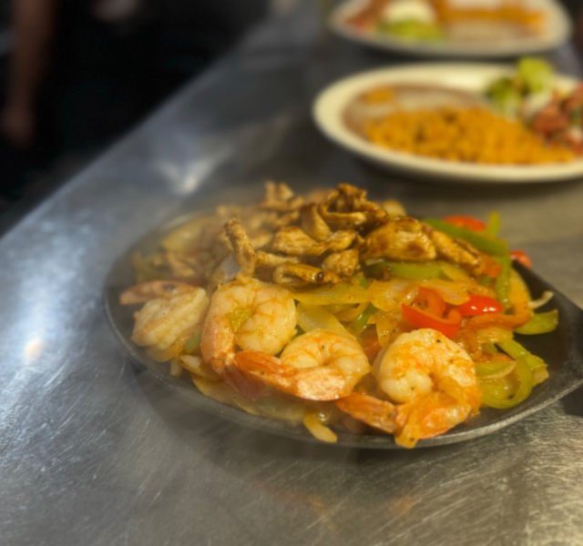 Sizzling mazatlan fajitas with chicken and shrimp, colorful onions, and bell peppers on a cast-iron skillet